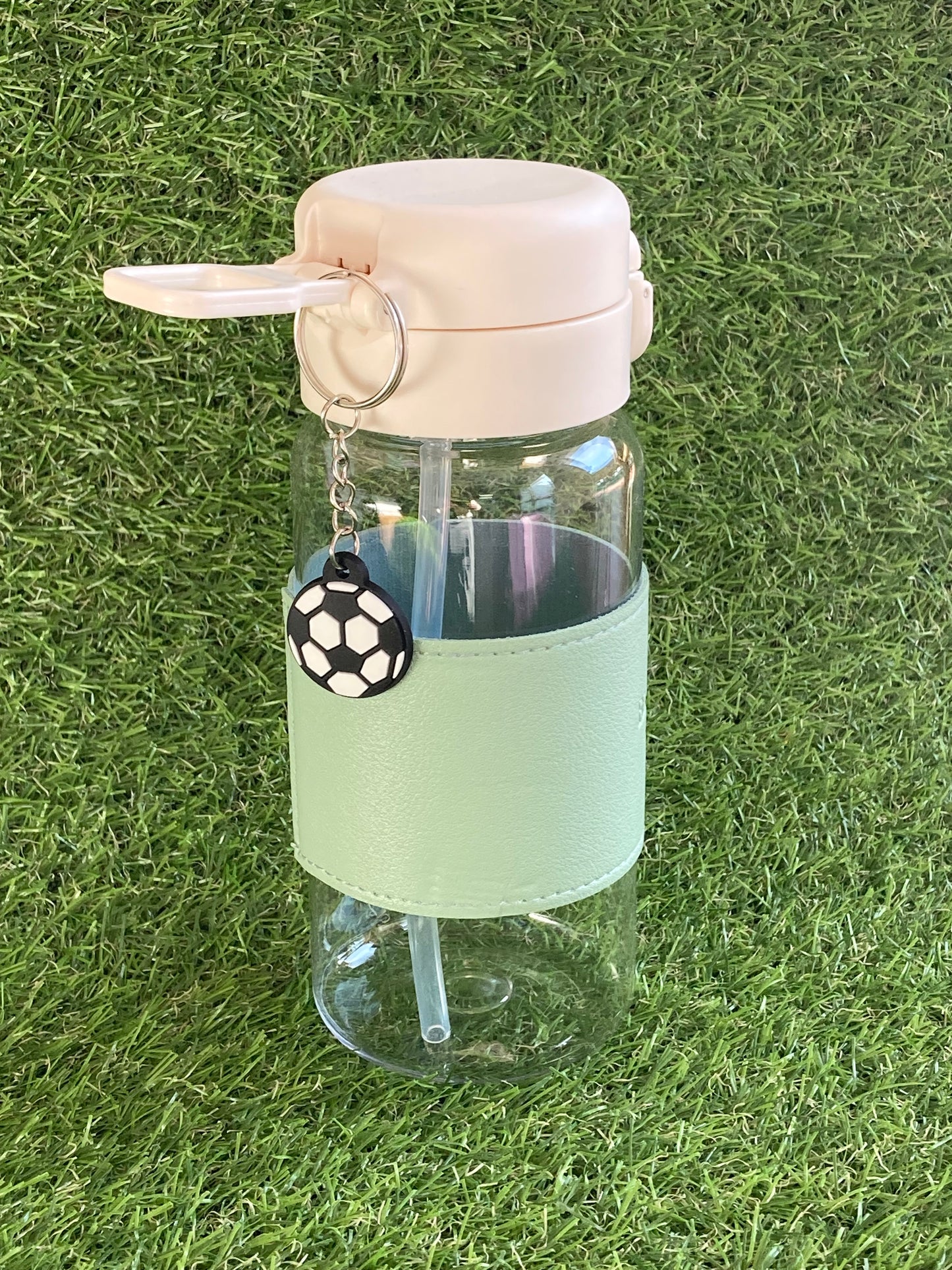 Clear plastic bottle with green sleeve and soccer ball key chain.