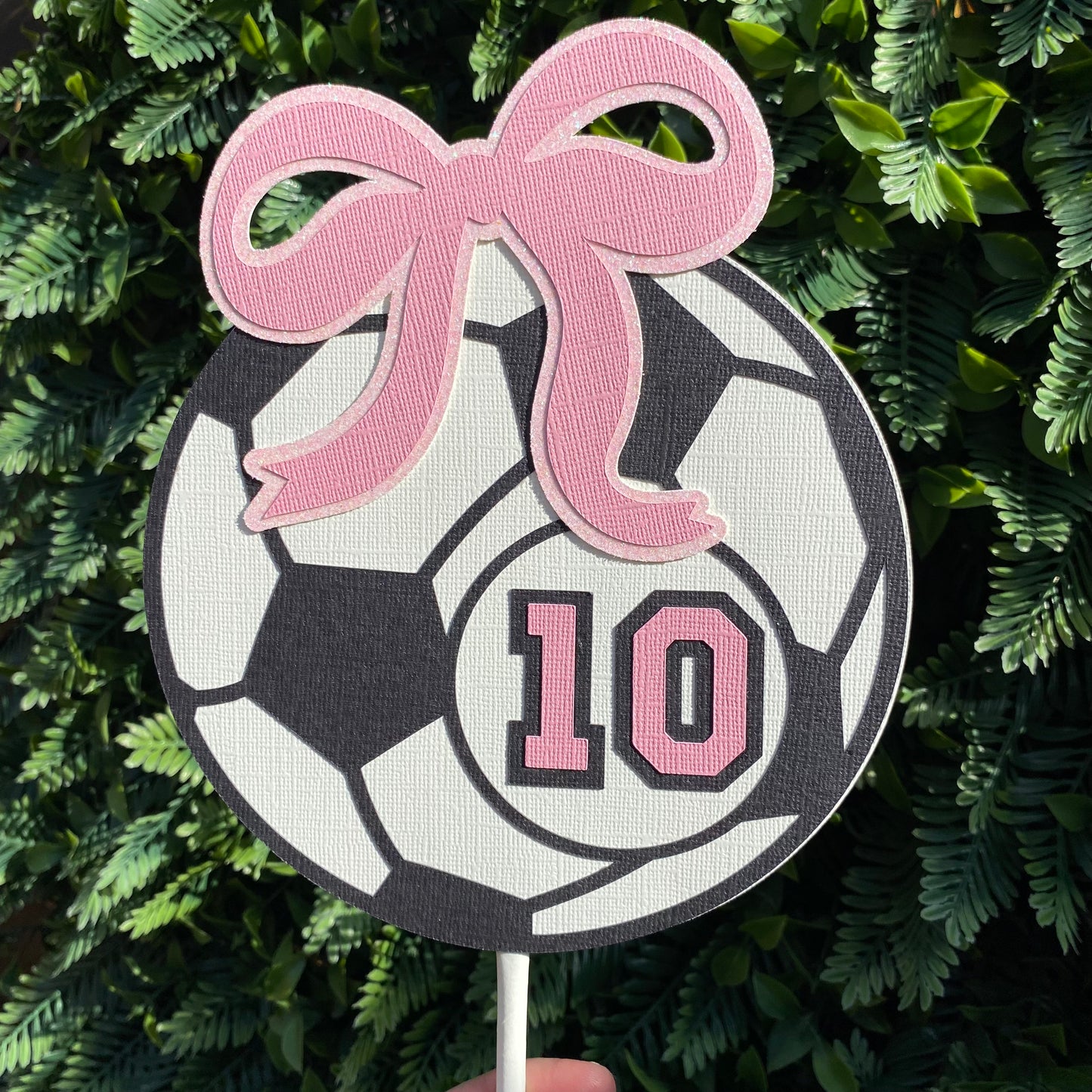 Girls giant soccer ball cake topper in black and white with a pink bow and the number 10 in pink.