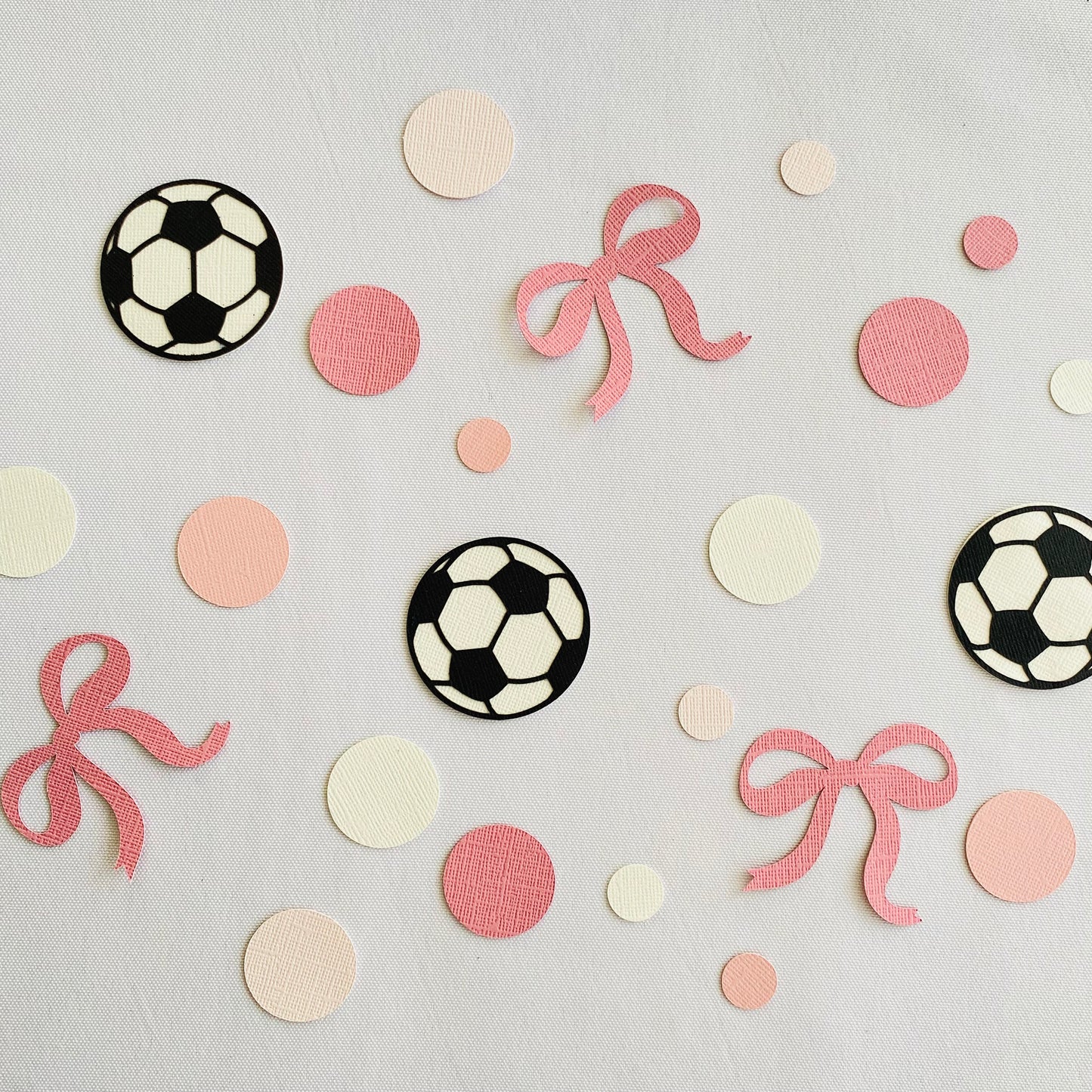 Party scatters of pink and white mixed size circles and black and white soccer balls with added pink bows.