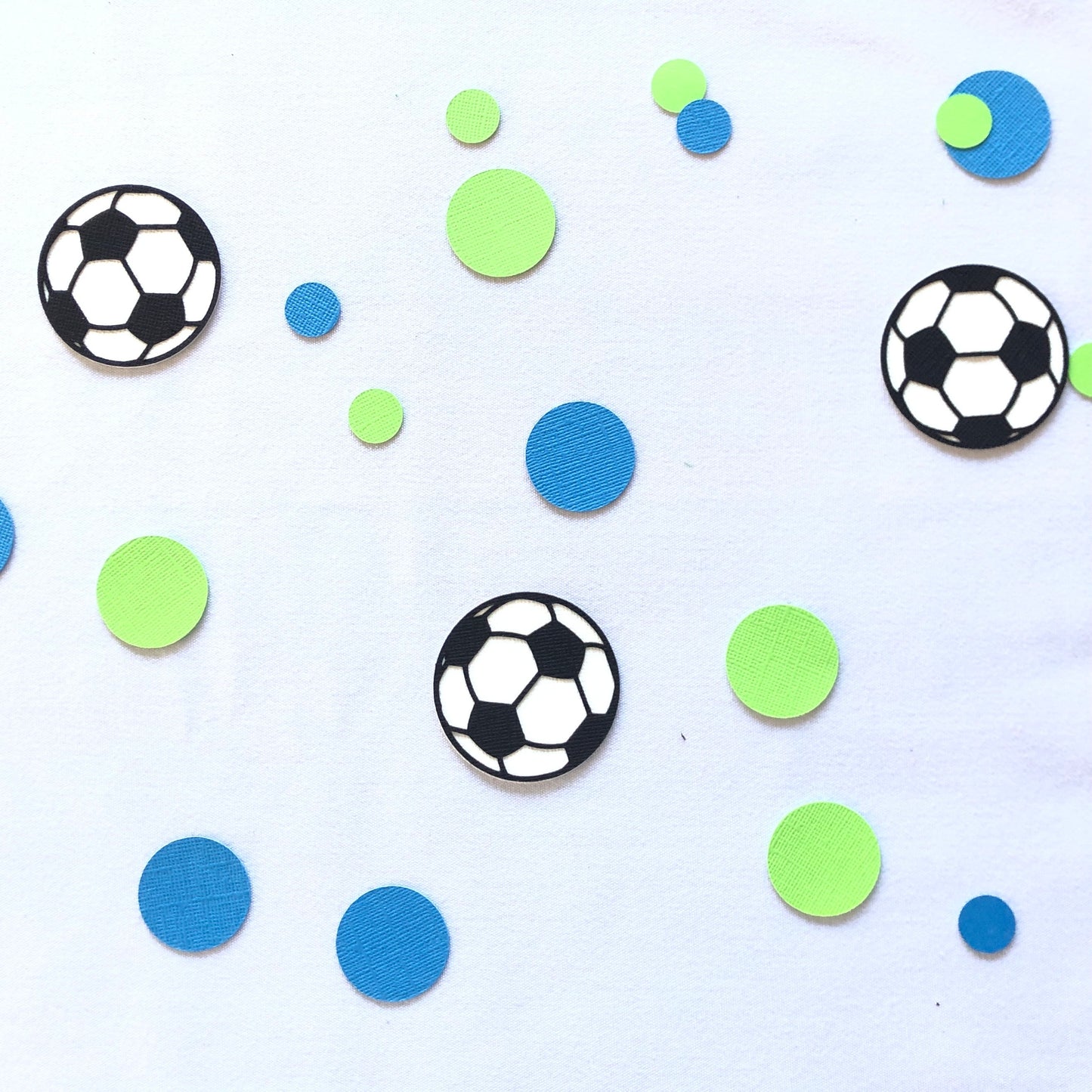 Round shape table scatters made from paper in blue and green with black and white soccer balls.