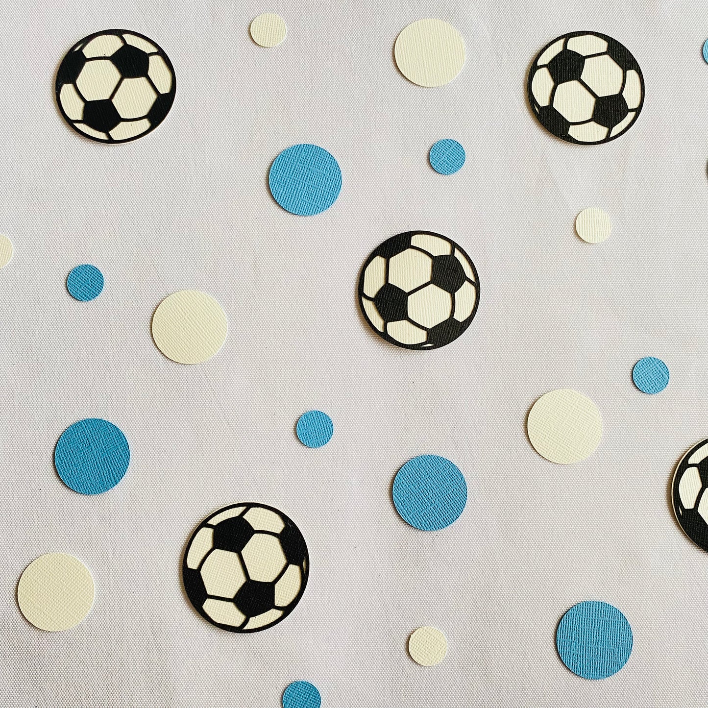 Blue and white round paper cutouts with soccer ball cutouts spread on synthetic grass
