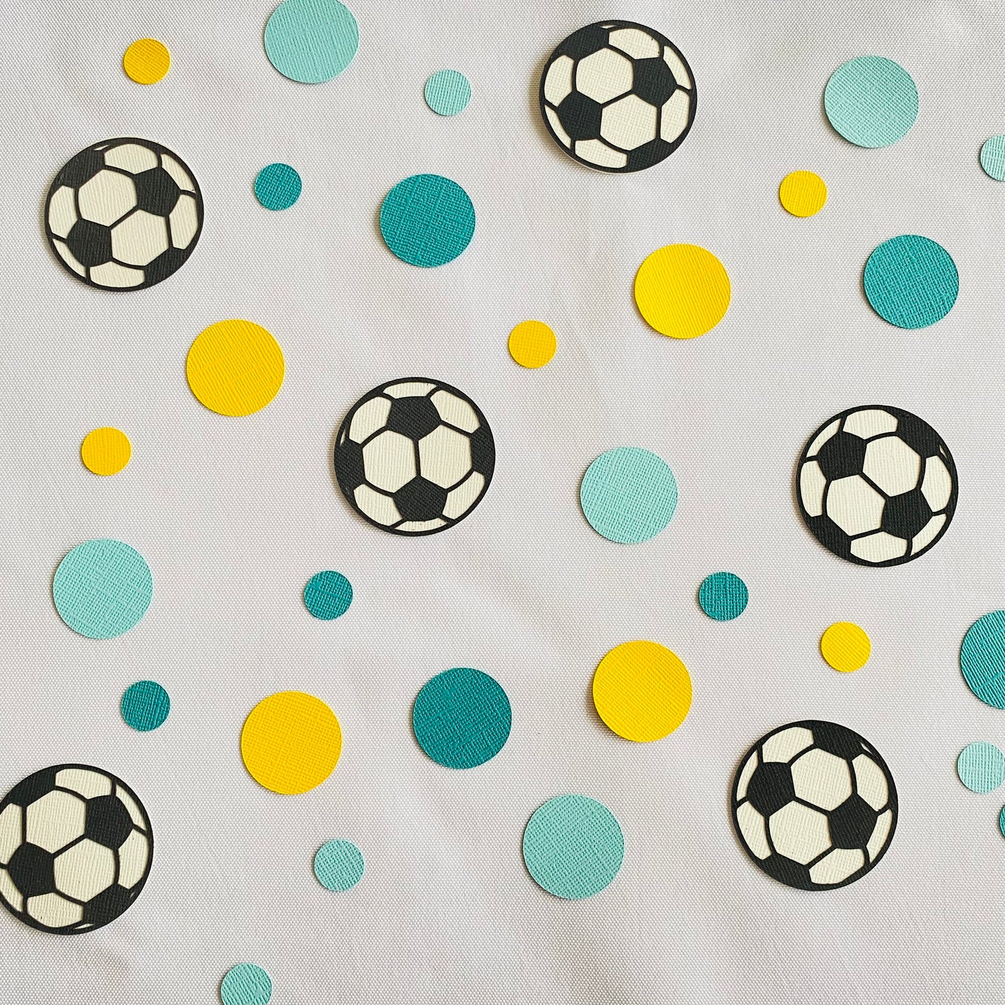 Yellow and blue round paper discs with black and white paper soccer balls scattered across a white table