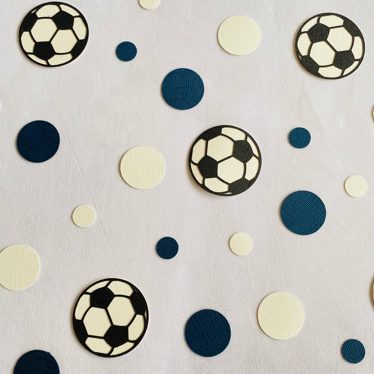 Blue and white round paper cutouts with soccer ball cutouts spread on a white table