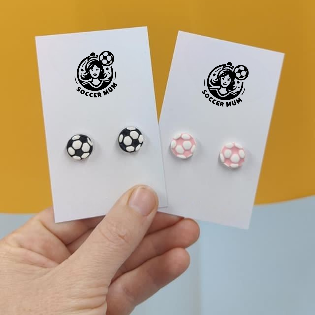 Pink and white stud soccer ball earrings on a earring board with Soccer Mum brand logo. Black and white stud soccer balls on earring board with Soccer Mum Brand logo.