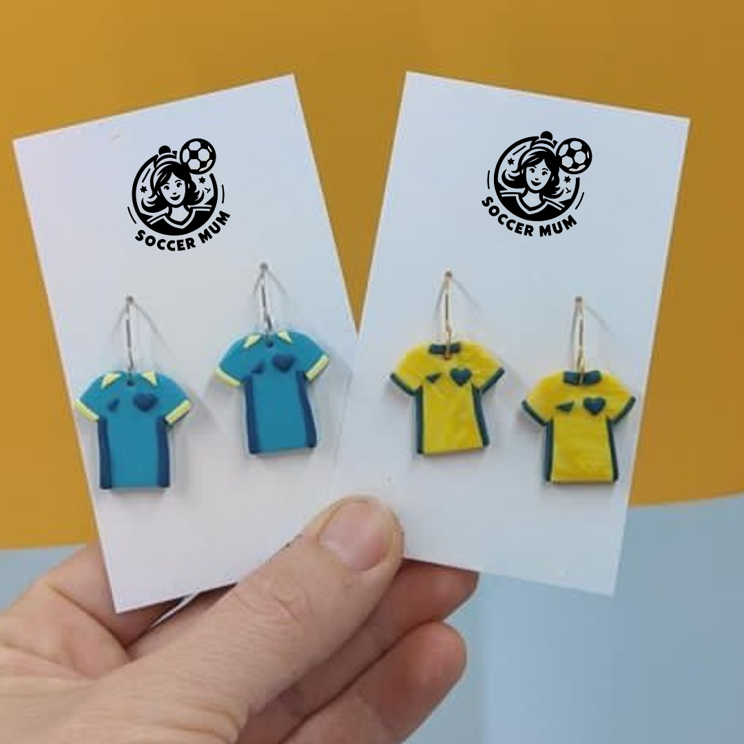 Yellow and green Socceroo Australian Shirt kits as dangle earrings on a earring board with Soccer Mum brand logo. Matilda teal and yellow soccer kit shirts on a earring board with Soccer Mum Brand logo.
