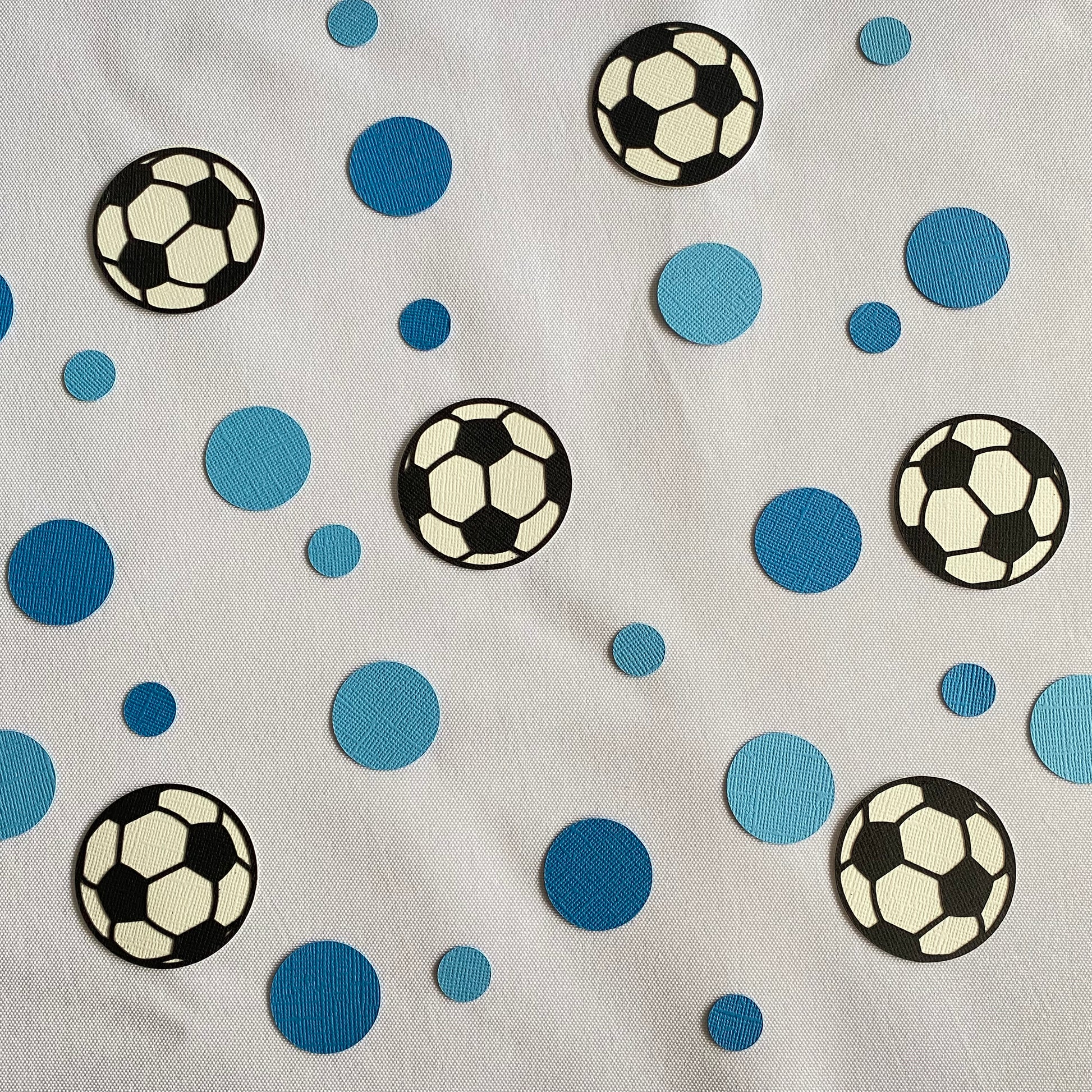 Large and small blue paper round discs with soccer ball paper discs  scattered across a white table