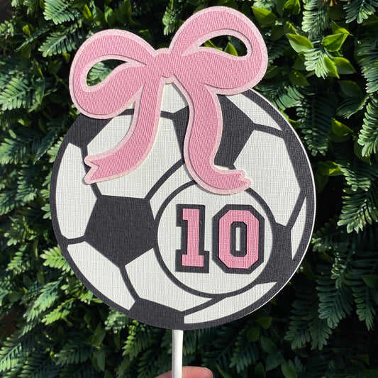 Girls giant soccer ball cake topper in black and white with a pink bow and the number 10 in pink.