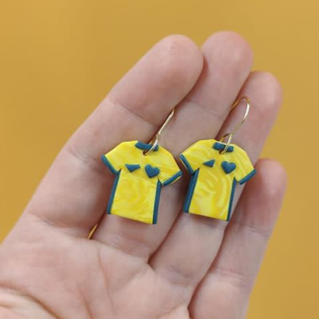 Yellow and green Socceroo Australian Shirt kits as dangle earrings laying on a hand to show size.